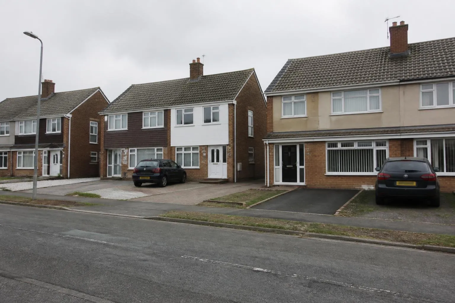 Example image: street of brick semi-detached houses with different driveway surfaces