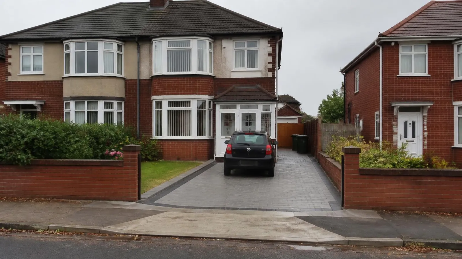 Example image: dropped kerb crossing leading onto a block-paved driveway outside a 1930s semi