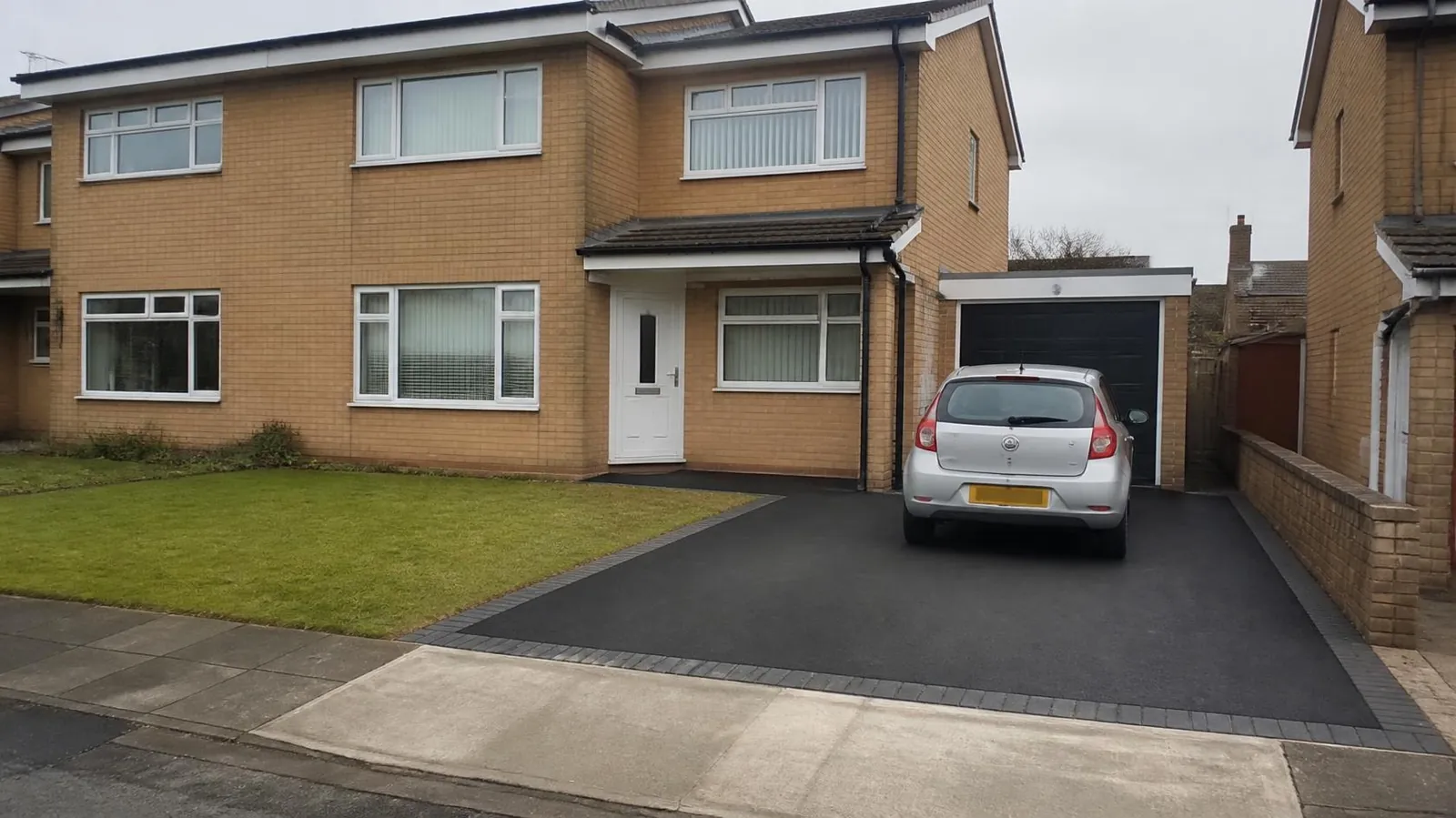 Example image: new black tarmac driveway with block edging in front of a semi-detached house