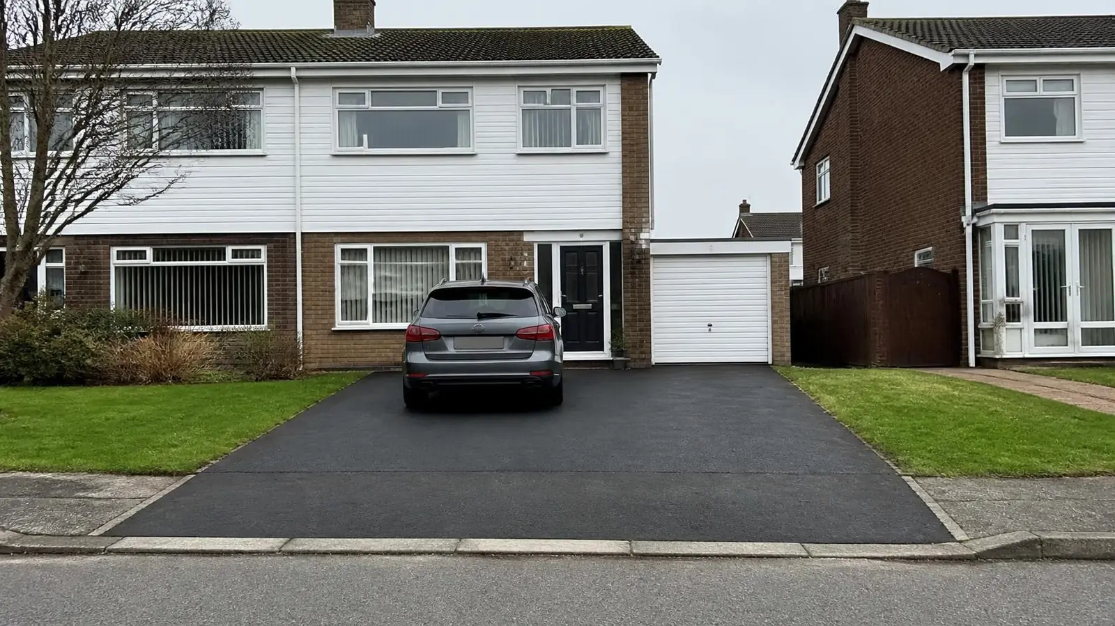 Example image: 1960s semi with a wide new tarmac driveway and an attached garage