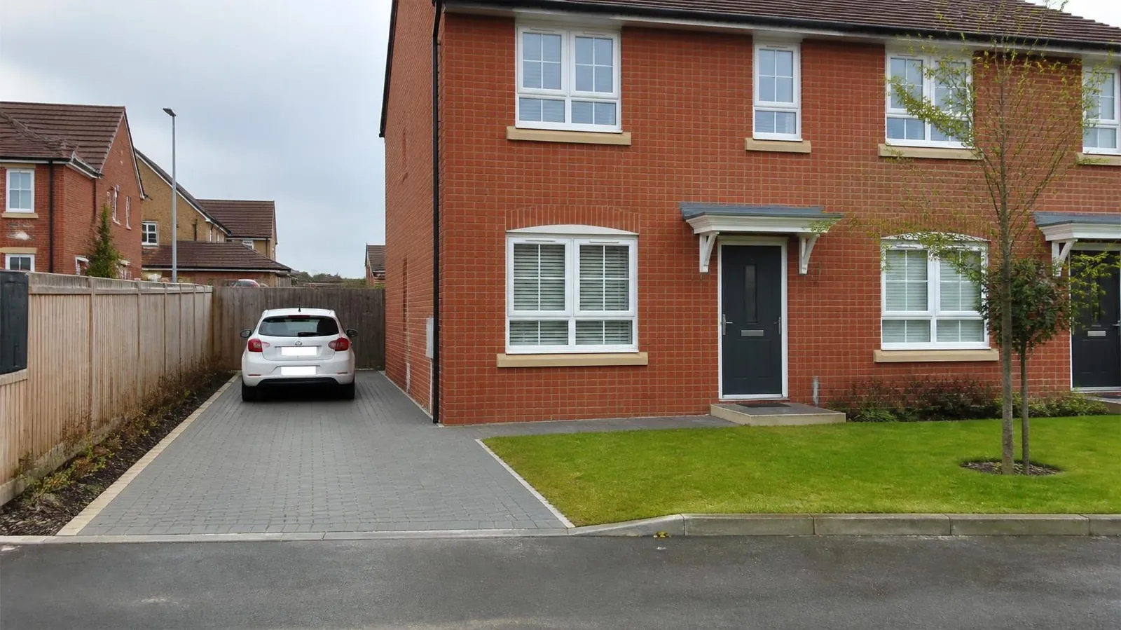 Example image: newer red-brick house with a grey block-paved driveway