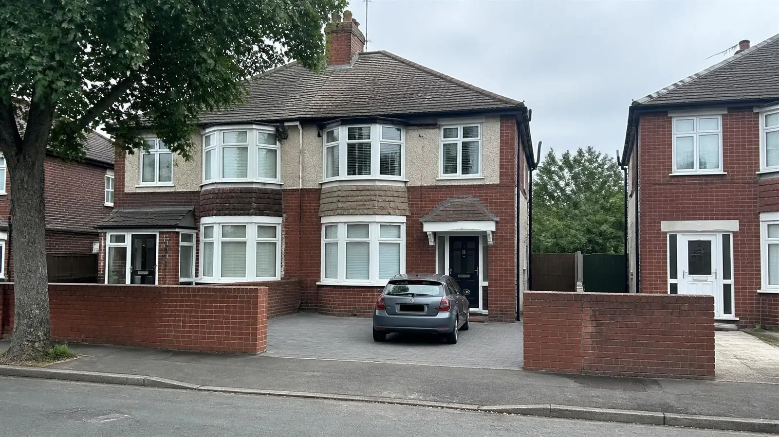 Example image: inter-war bay-fronted semi with a block-paved drive behind a low brick wall